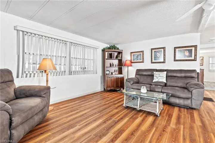 Living room featuring a textured ceiling, wood finished floors, and ceiling fan