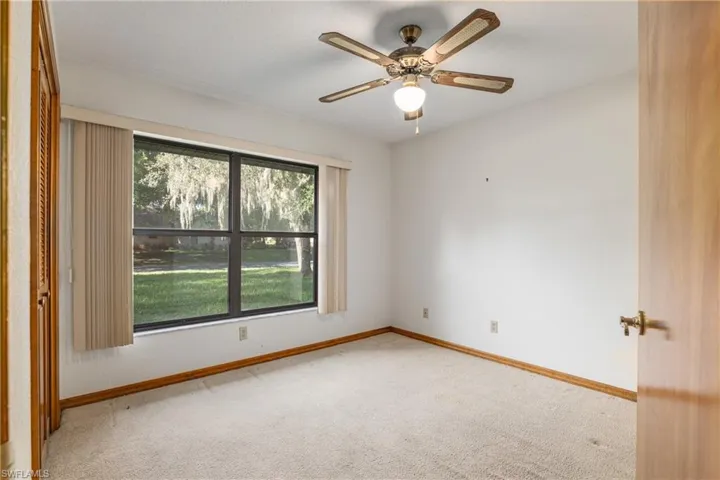 Empty room featuring light colored carpet, a wealth of natural light, and ceiling fan