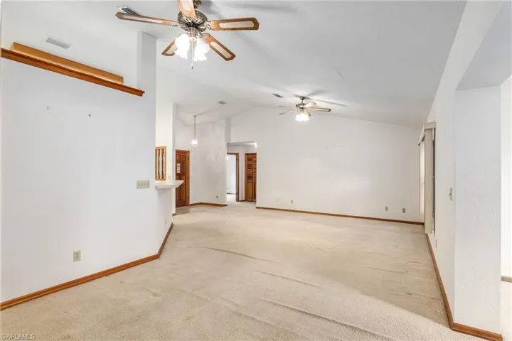 Unfurnished room featuring light colored carpet, high vaulted ceiling, and ceiling fan