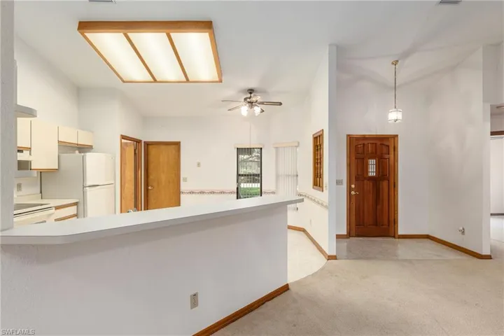 Carpeted foyer entrance with a towering ceiling and ceiling fan