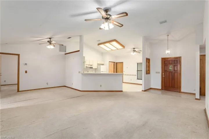 Unfurnished living room featuring light colored carpet, high vaulted ceiling, and ceiling fan