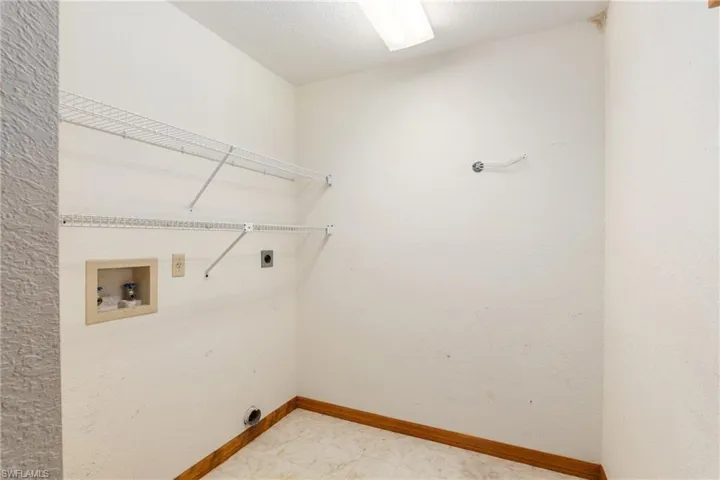 Clothes washing area featuring hookup for an electric dryer, tile patterned flooring, and washer hookup