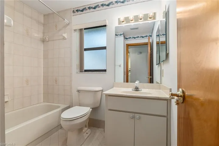 Full bathroom with tile patterned floors, vanity, tiled shower / bath combo, and toilet