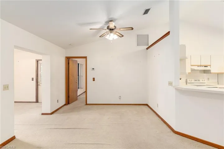Carpeted spare room with high vaulted ceiling and ceiling fan