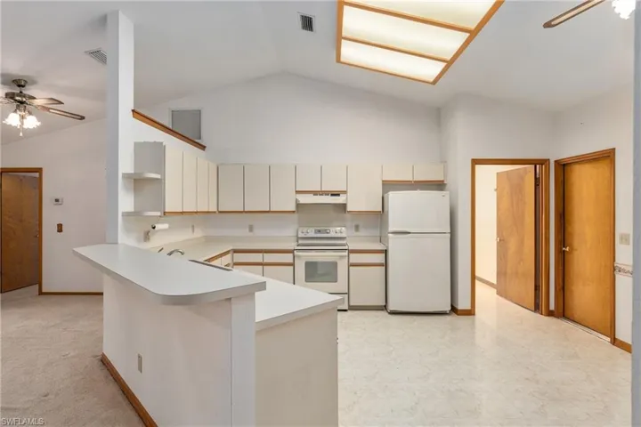 Kitchen featuring light tile patterned floors, ceiling fan, cream cabinetry, white appliances, and kitchen peninsula