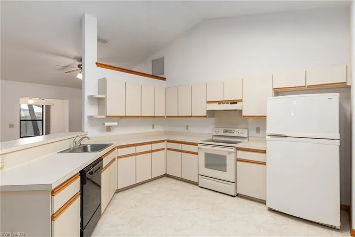 Kitchen with light tile patterned flooring, white appliances, sink, and ceiling fan