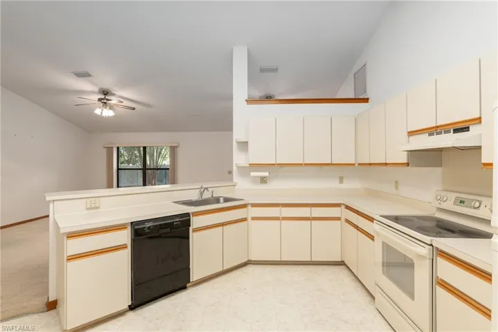 Kitchen with electric range, kitchen peninsula, dishwasher, ceiling fan, and light carpet