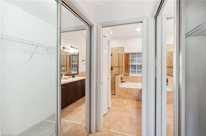 Bathroom featuring a garden tub, vanity, a spacious closet, tile patterned flooring, and a tile shower