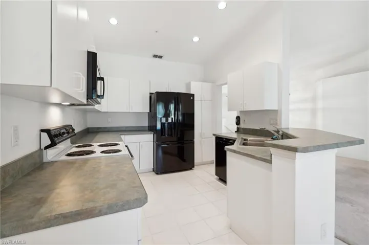 Kitchen featuring black appliances, a sink, a peninsula, white cabinetry, and recessed lighting