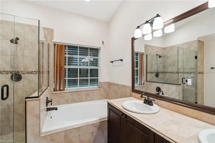 Full bath featuring a garden tub, a stall shower, and double vanity