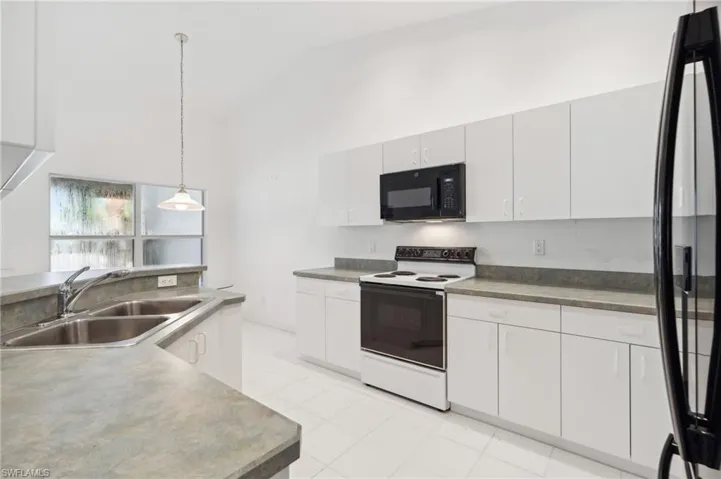 Kitchen with black appliances, a sink, pendant lighting, light tile patterned flooring, and white cabinets