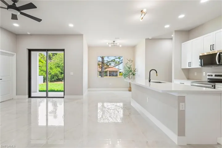 Kitchen featuring white cabinetry, stainless steel appliances, light stone counters, ceiling fan, and recessed lighting
