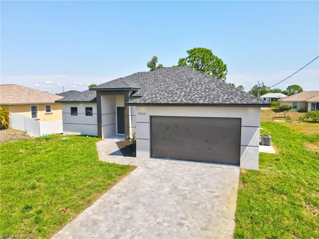 View of front of property featuring stucco siding, driveway, roof with shingles, and an attached garage