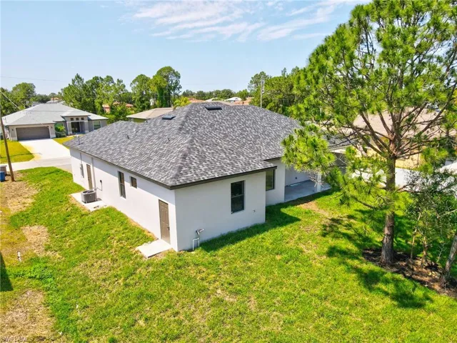 View of property exterior with stucco siding, a lawn, and roof with shingles
