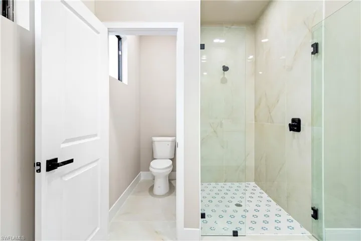 Full bathroom featuring a marble finish shower and toilet