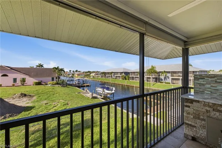 Screened balcony featuring a built-in outdoor kitchen with a stone facade, granite-style countertop, and a mosaic tile backsplash