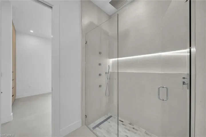 Glass-enclosed walk-in shower with rain shower head and body jets