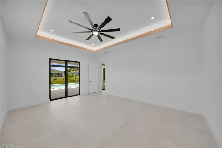 Recessed lighting accentuates the tray ceiling with wood-finish trim and a modern ceiling fan