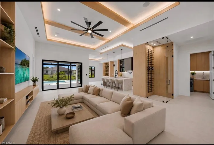Spacious open-concept living area featuring a coffered ceiling with recessed lighting and a ceiling fan