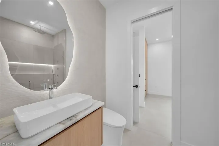 Modern vanity featuring a rectangular vessel sink, stone countertop, and light wood-finish cabinetry