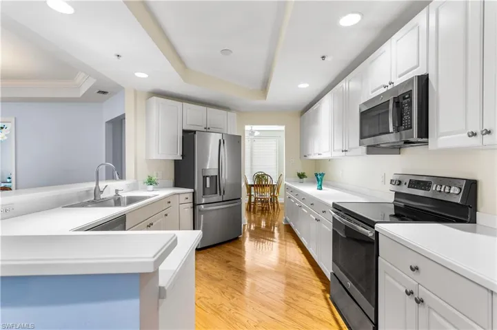The huge white kitchen is equipped with plenty of cabinets, newer stainless-steel appliances, and a breakfast or cocktail sitting bar area.