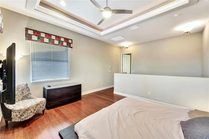 Bedroom with a tray ceiling, ceiling fan, and hardwood / wood-style floors