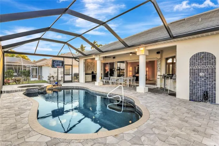 View of pool with glass enclosure, area for grilling, an in ground hot tub, and a patio