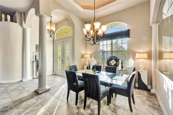 Dining area with a raised ceiling, french doors, crown molding, and a chandelier