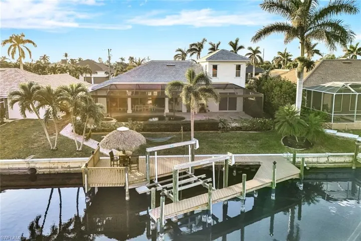 View of dock with a yard, a water view, and glass enclosure