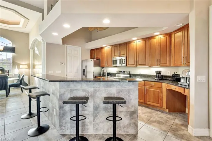 Kitchen featuring a kitchen bar, appliances with stainless steel finishes, vaulted ceiling, a kitchen island with sink, and sink