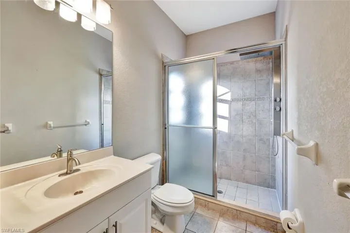 Bathroom with tile patterned floors, vanity, toilet, and a shower with shower door