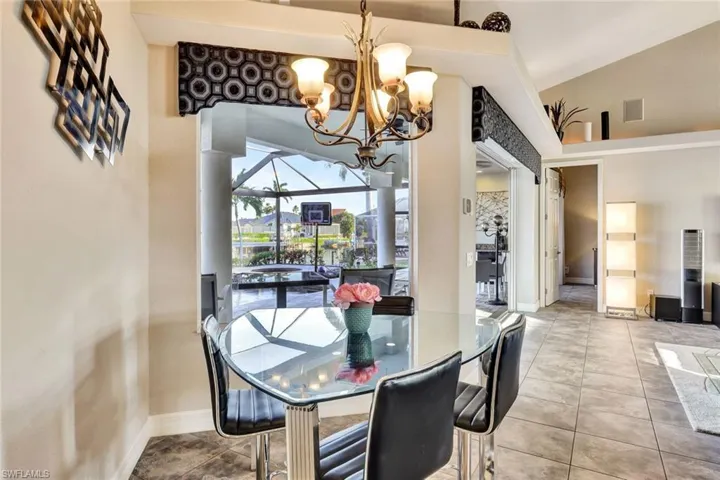 Dining room featuring light tile patterned flooring, vaulted ceiling, and an inviting chandelier