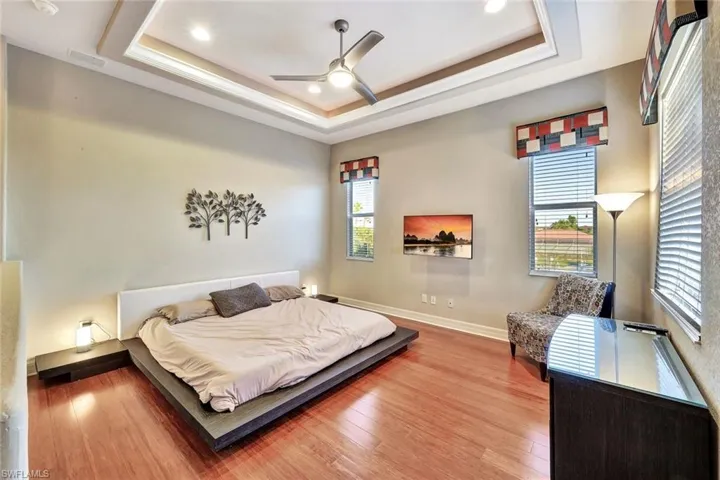 Bedroom featuring multiple windows, a raised ceiling, and ceiling fan