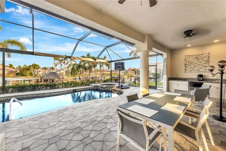 View of swimming pool with an in ground hot tub, glass enclosure, ceiling fan, and a patio area