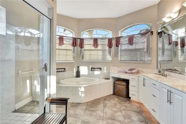 Bathroom with tile patterned floors, vanity, and shower with separate bathtub