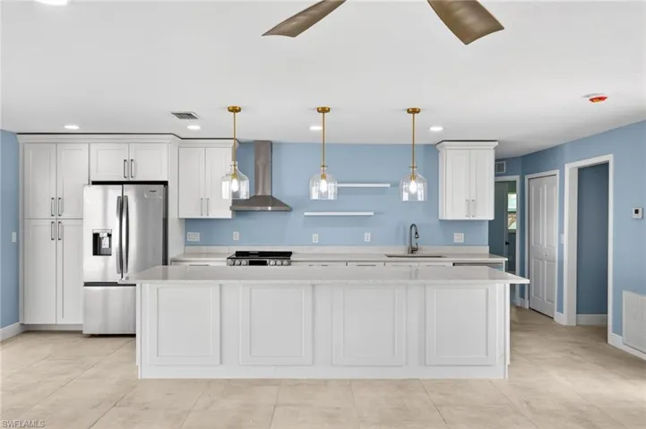 Kitchen featuring white shaker cabinetry, stainless steel appliances, a center island with countertop seating, and light-toned tile flooring