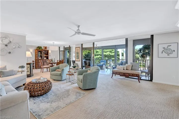 Living area featuring ceiling fan, light carpet, floor to ceiling windows, and ornamental molding