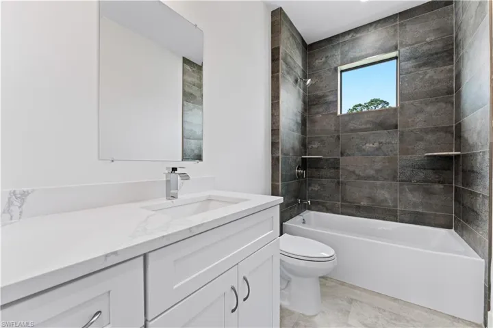 Full bathroom featuring toilet, tiled shower / bath combo, and vanity
