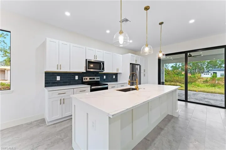 Kitchen featuring a kitchen island with sink, white cabinets, sink, and stainless steel appliances