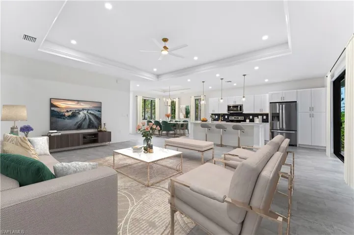 Living room featuring ceiling fan and a tray ceiling - photo enhanced with virtual staging.