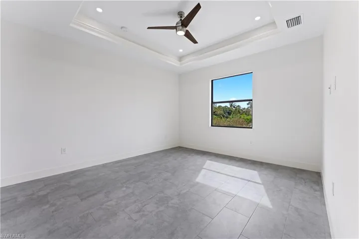 This master bedroom has a tray ceiling with a fan, and the ceiling is raised, which makes the room feel more spacious.