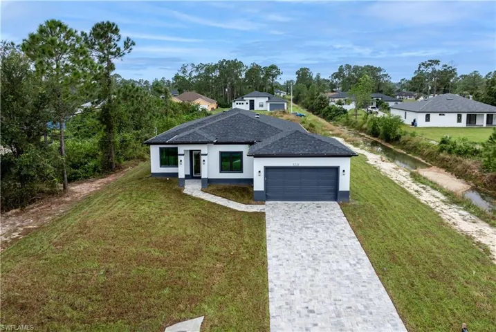 View of front of house featuring a garage and a front yard, next to canal