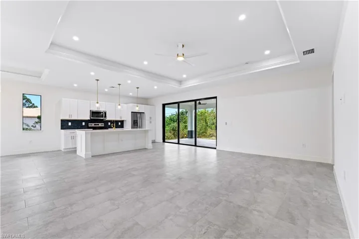 Unfurnished living room featuring ceiling fan and a tray ceiling