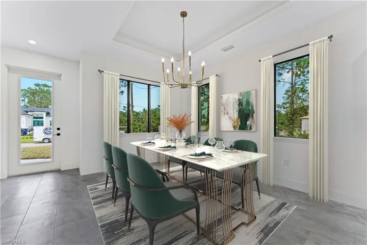 Dining space featuring a notable chandelier, plenty of natural light, and a tray ceiling photo enhanced with virtual staging.