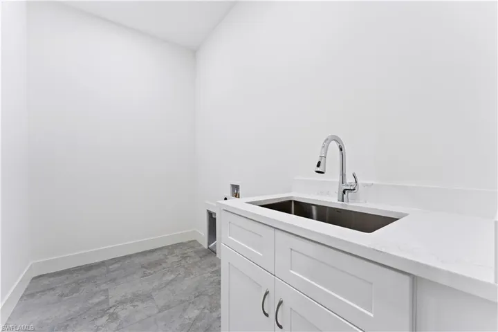 Clothes washing area featuring cabinets, hookup for a washing machine, and sink