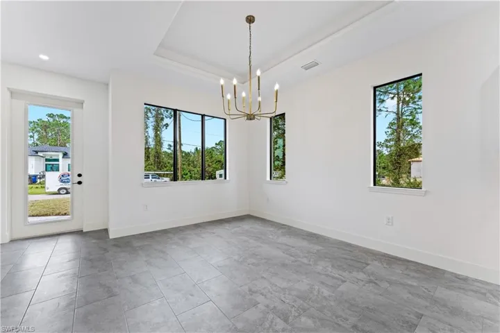Dining room with beautiful chandelier, plenty of natural light, and a tray ceiling