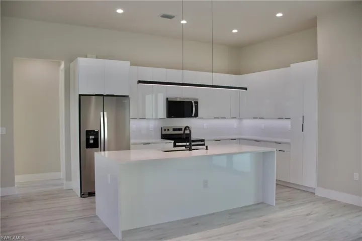 Kitchen with white cabinetry, a sink, an island with sink, and appliances with stainless steel finishes