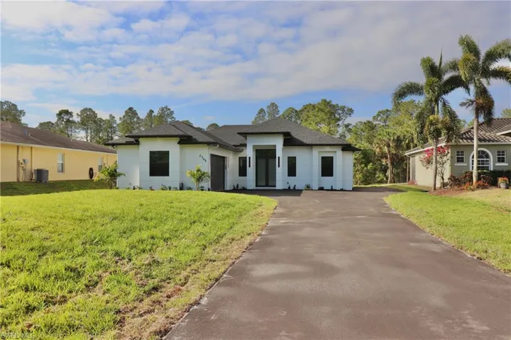 Prairie-style house with aphalt driveway, cooling unit, and a front yard