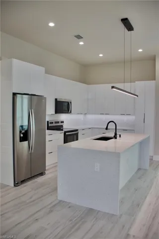 Kitchen with white cabinets, stainless steel appliances, a sink, visible vents, and modern cabinets
