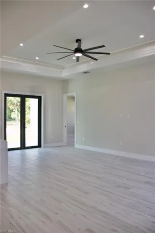 Unfurnished room with ceiling fan, a tray ceiling, light wood finished floors, baseboards, and recessed lighting